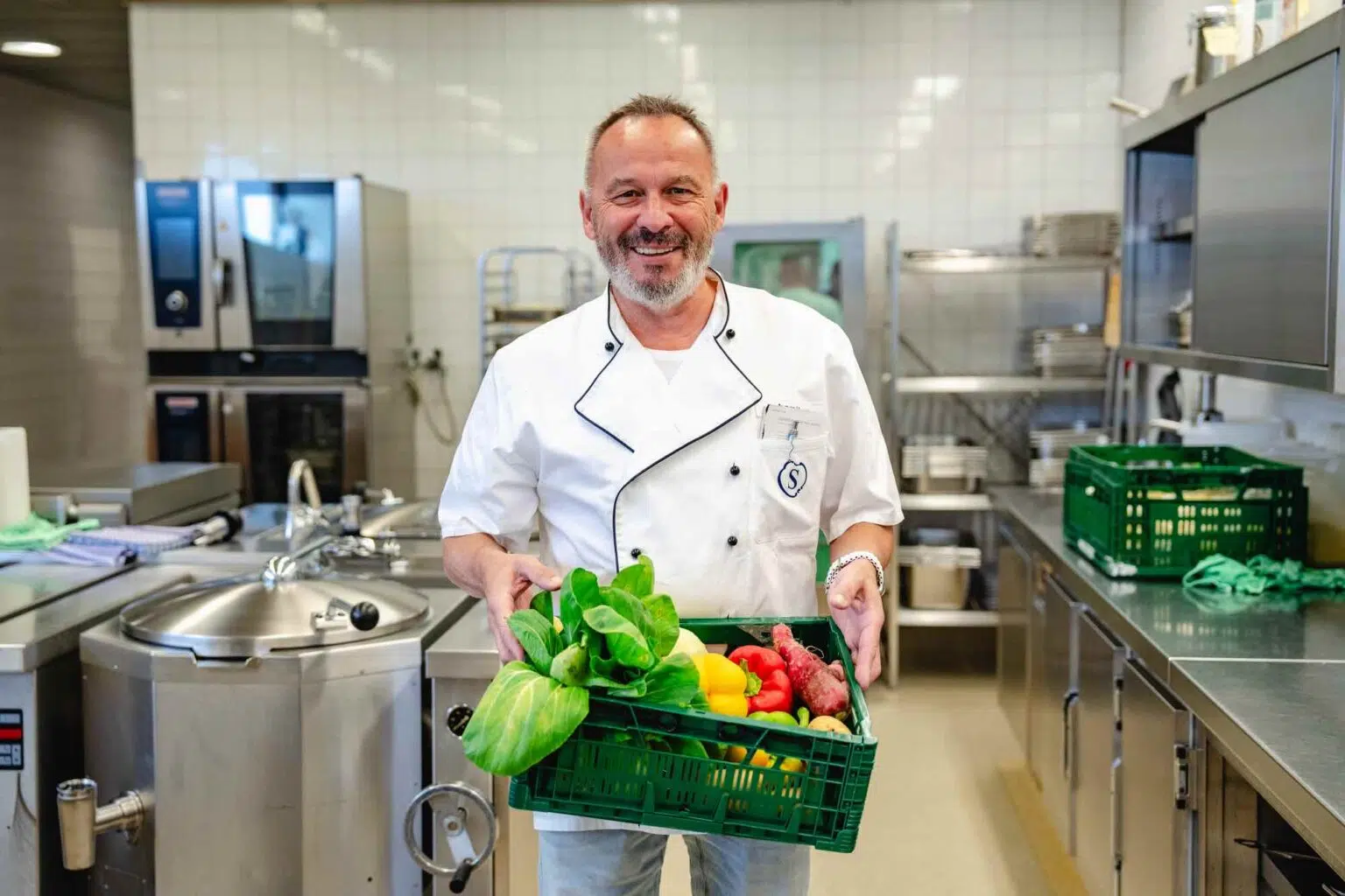 Uwe Anhorn in der Küche mit einer Kiste frischem Gemüse